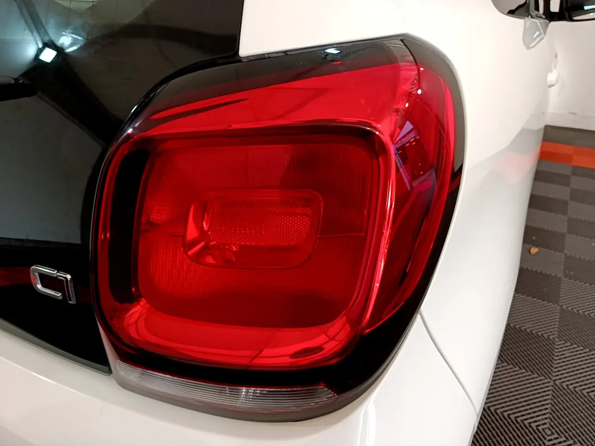 Gros plan sur le feu arrière droit rouge d'une Citroën C1 blanche, version 2020, avec partie arrière noire brillante.