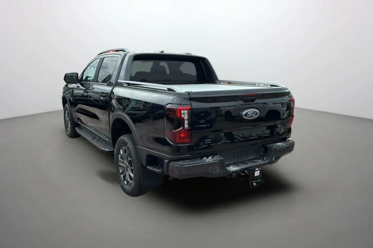 Ford Ranger 2.0 Wildtrak noir agate vu en 3/4 arrière droit avec arceau sport et attelage visible.