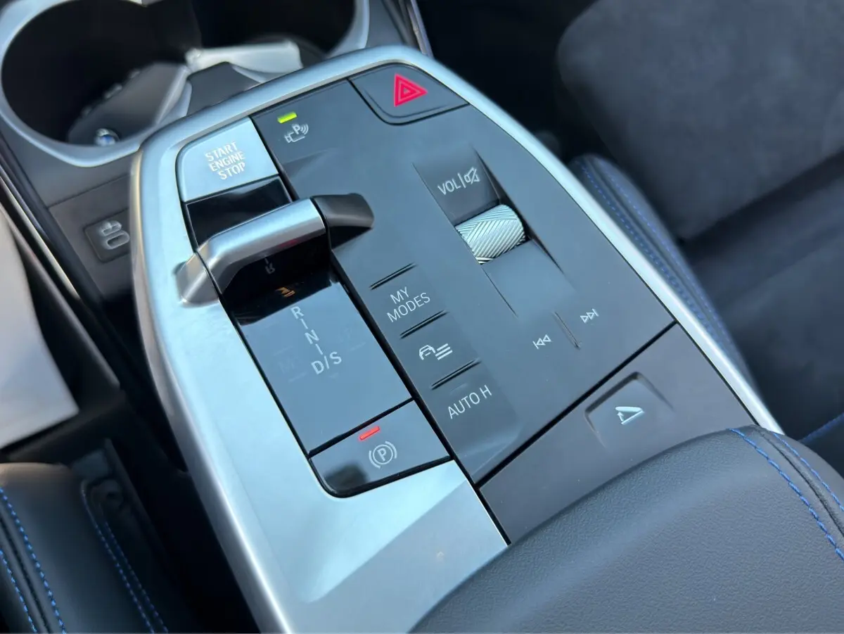 Vue rapprochée de la console centrale noire et argentée du BMW X1 M SPORT 2025 avec surpiqûres bleues.