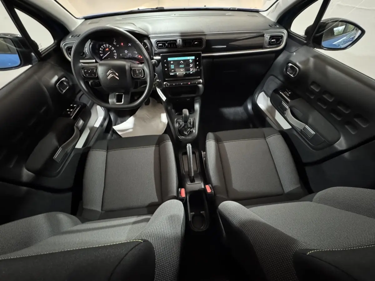 Vue intérieure avant de la Citroën C3 2018, tableau de bord noir avec écran tactile et sièges tissu gris.