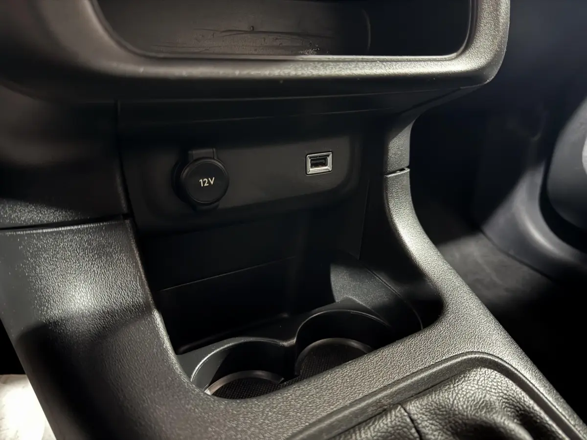 Vue rapprochée de la console centrale noire de la Citroën C3 avec prise 12V et port USB visibles.