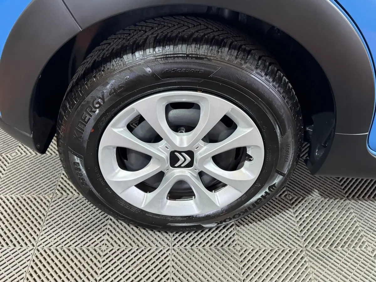 Gros plan sur la roue avant droite d'une Citroën C3 bleu, avec jante argentée et logo Citroën central.