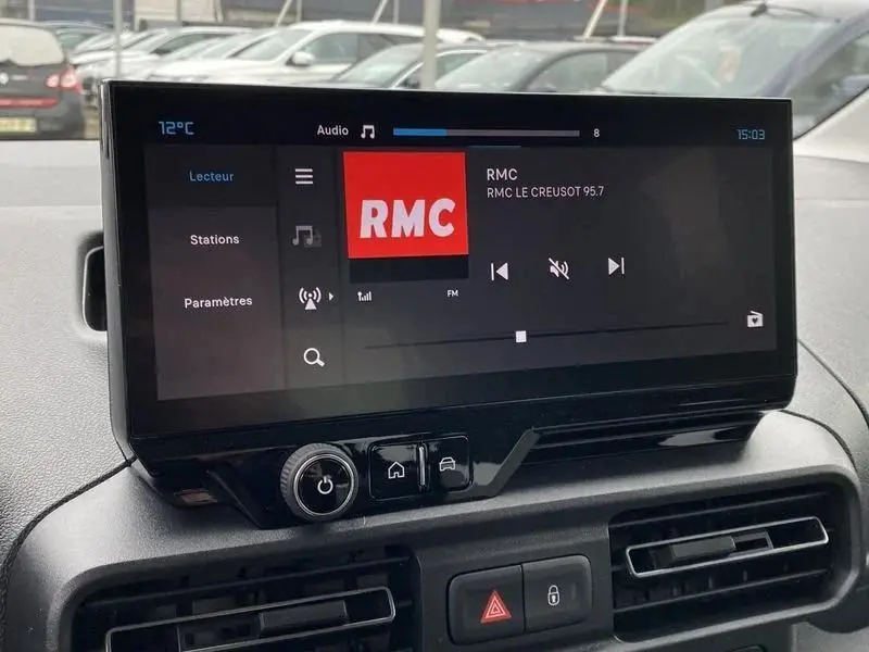 Écran tactile central du tableau de bord du Citroën Berlingo gris Artense, affichant la radio RMC en FM.
