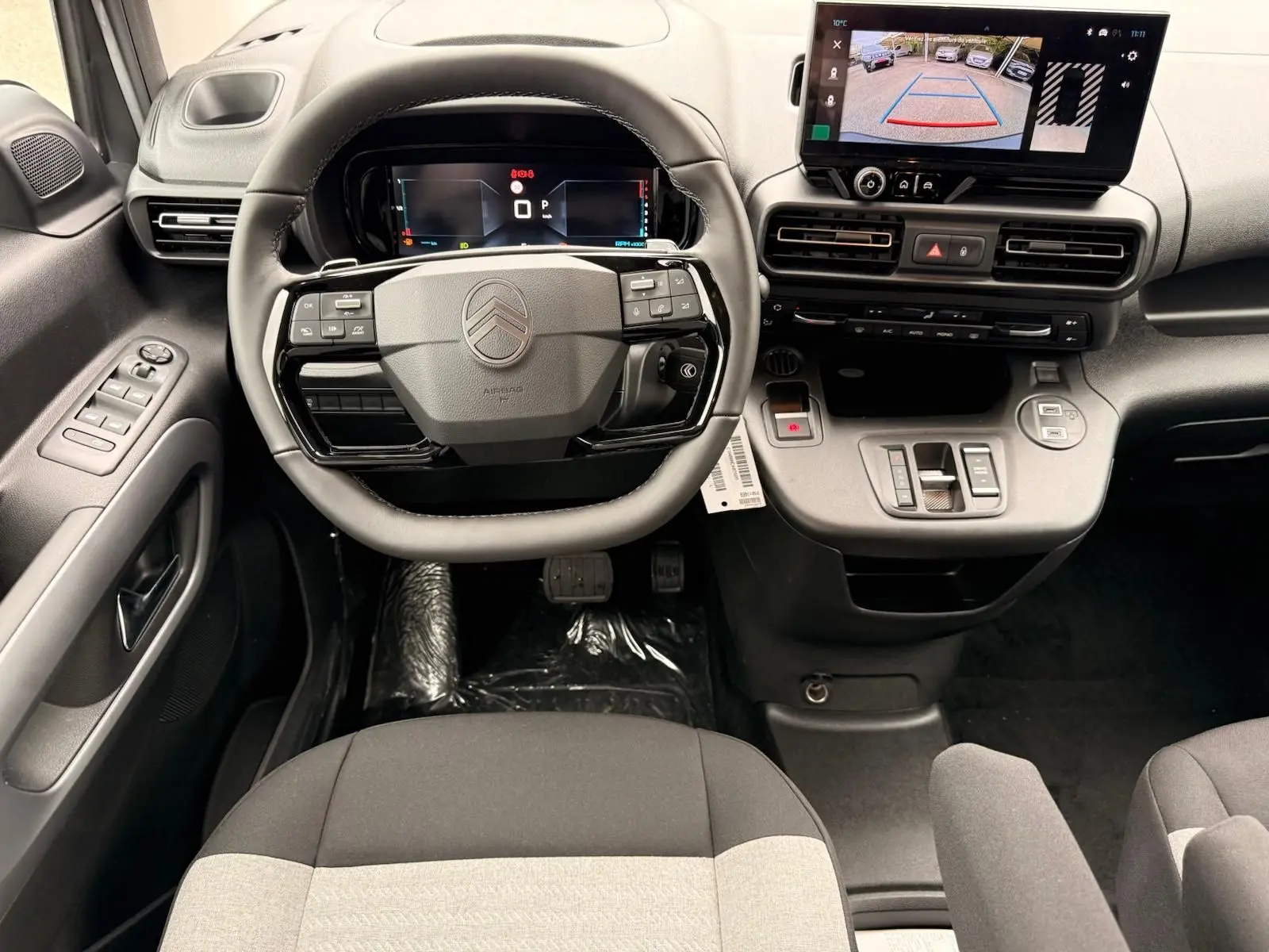 Vue intérieure centrée sur le volant et tableau de bord du Citroën Berlingo gris Artense avec écran tactile et caméra de recul.