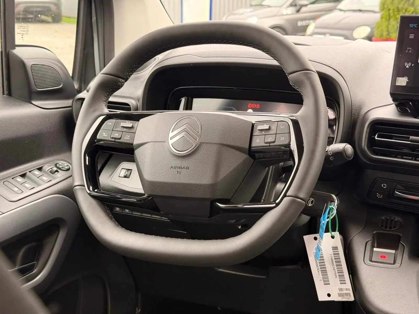 Vue rapprochée du volant cuir noir du Citroën Berlingo 2025, avec commandes intégrées et tableau de bord numérique.