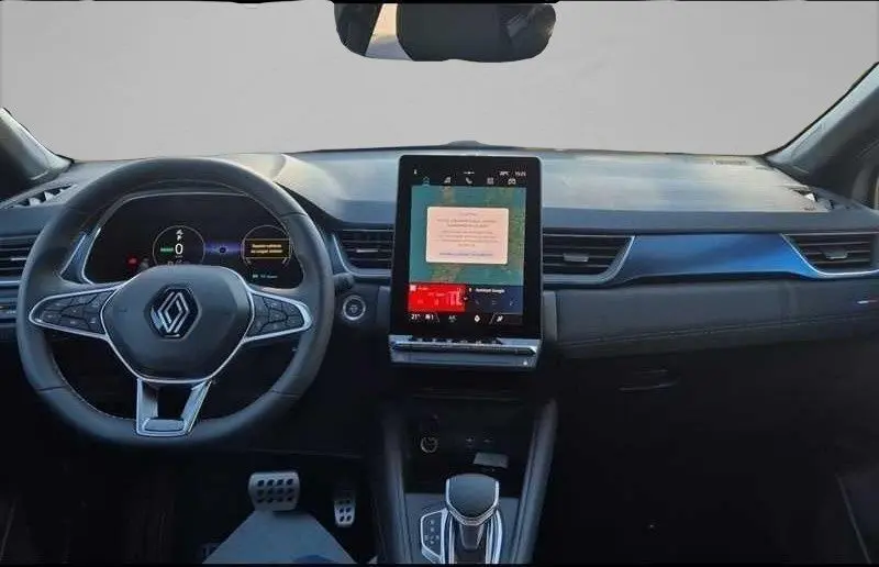 Intérieur avant du Renault Captur E-Tech hybride 2025, tableau de bord noir avec écran tactile vertical et volant multifonction.