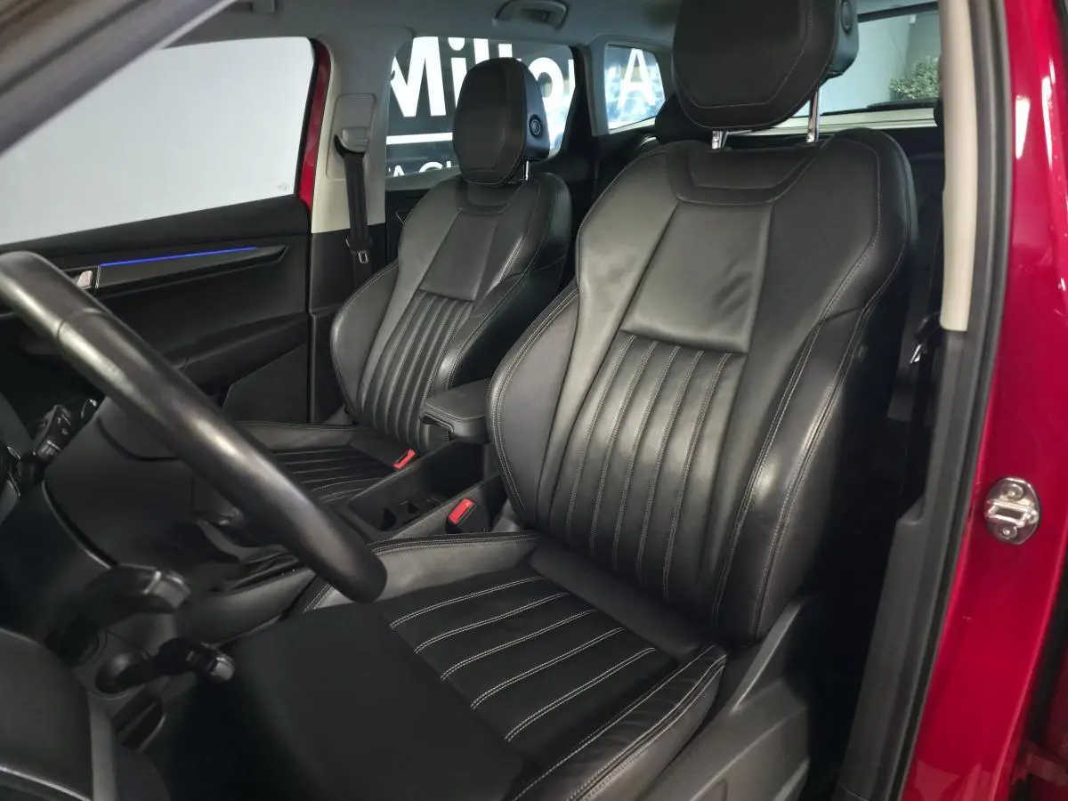 Intérieur du SKODA KAROQ rouge, vue côté gauche sur sièges avant en cuir noir avec surpiqûres blanches.