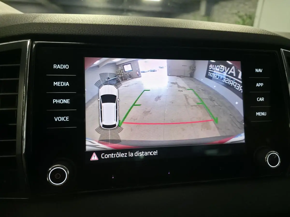 Affichage caméra de recul avec vue 360° du Skoda Karoq rouge, guidage de trajectoire et alertes de distance.