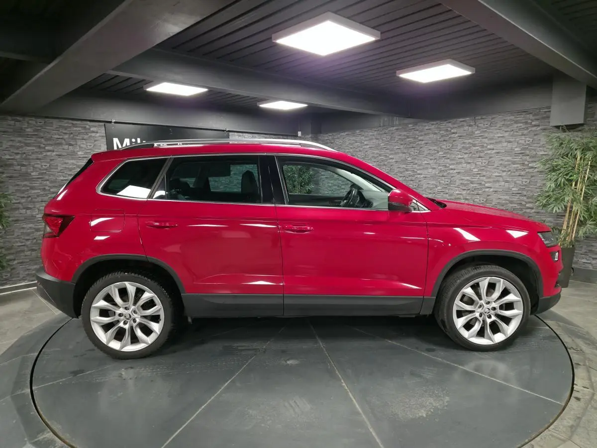 Profil droit d'un SKODA KAROQ rouge 2018 avec jantes alliage 19 pouces et arches de roues en plastique noir.