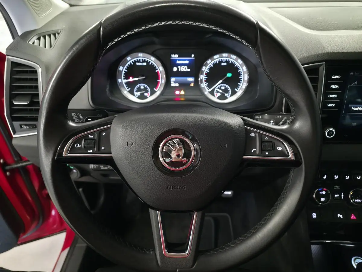 Vue rapprochée du volant cuir noir avec logo SKODA et tableau de bord numérique du Karoq rouge 2018.