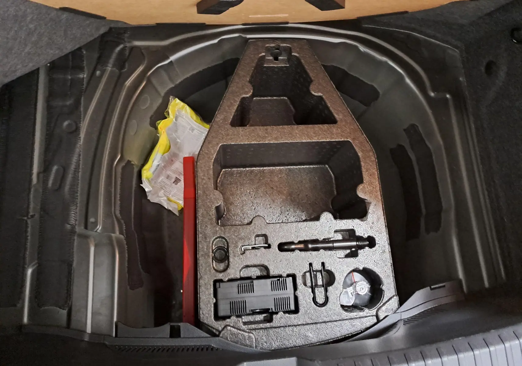 Coffre ouvert du SEAT Ibiza 2024 noir minuit, vue plongeante sur le rangement sous plancher avec outils et accessoires.