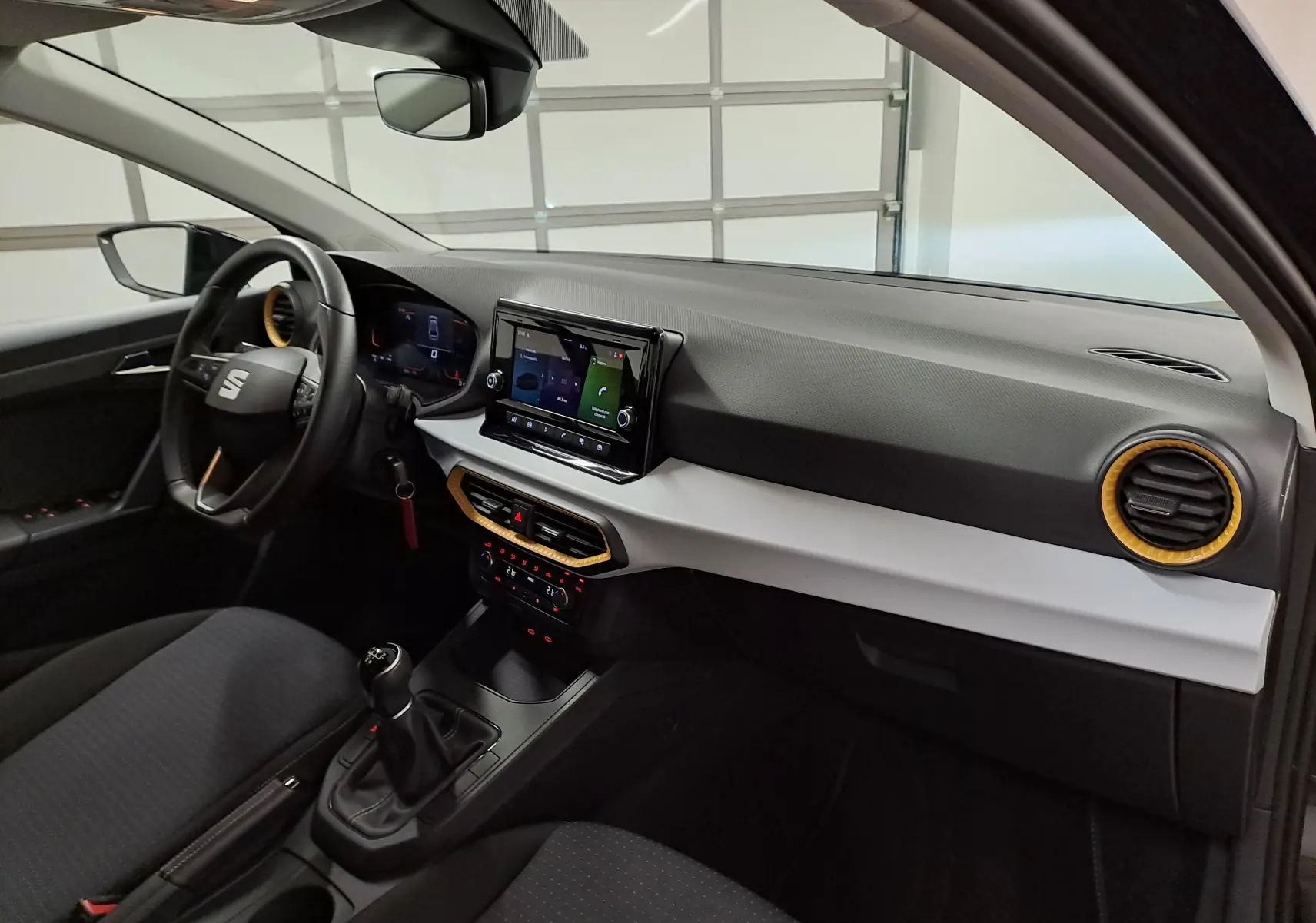 Intérieur de la SEAT Ibiza 2024 noir minuit, vue côté conducteur montrant tableau de bord avec écran tactile et détails orange.