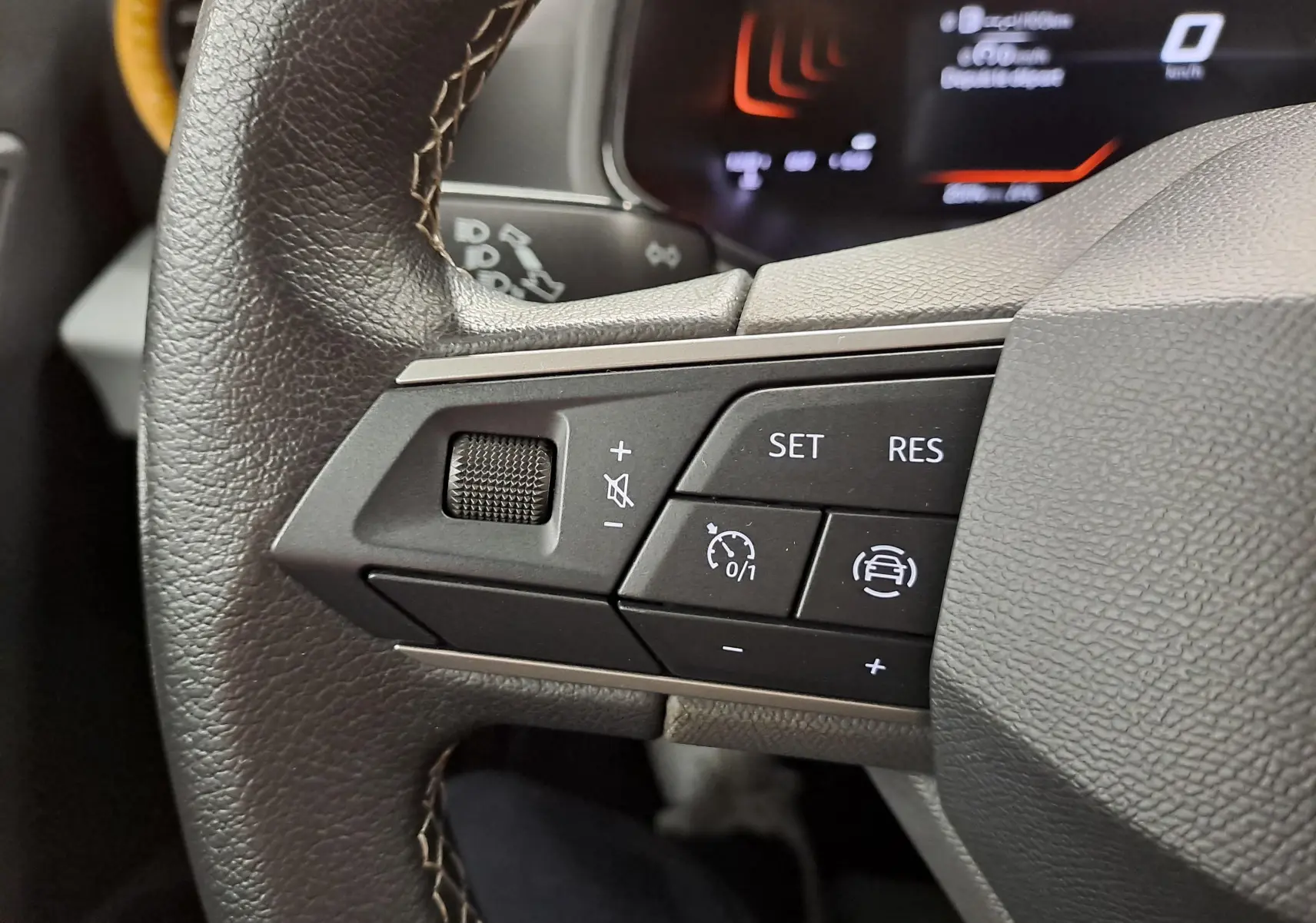 Gros plan sur les commandes au volant côté gauche du SEAT Ibiza 2024 noir minuit, avec réglages du régulateur de vitesse.