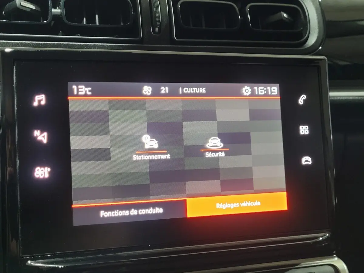 Gros plan sur l'écran tactile central de la Citroën C3 beige, affichant les options de stationnement et sécurité.
