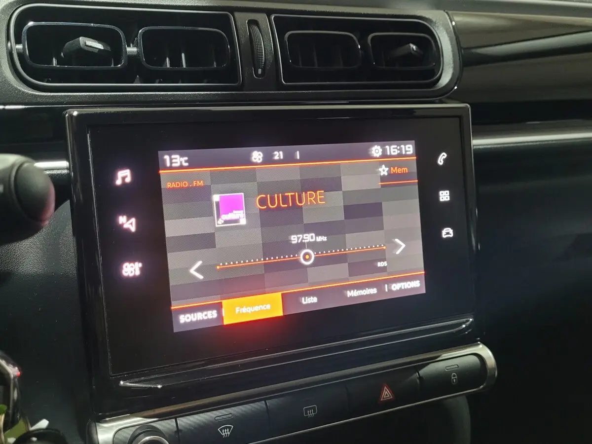 Vue rapprochée de l'écran tactile central du tableau de bord de la Citroën C3 beige, affichant une radio FM.