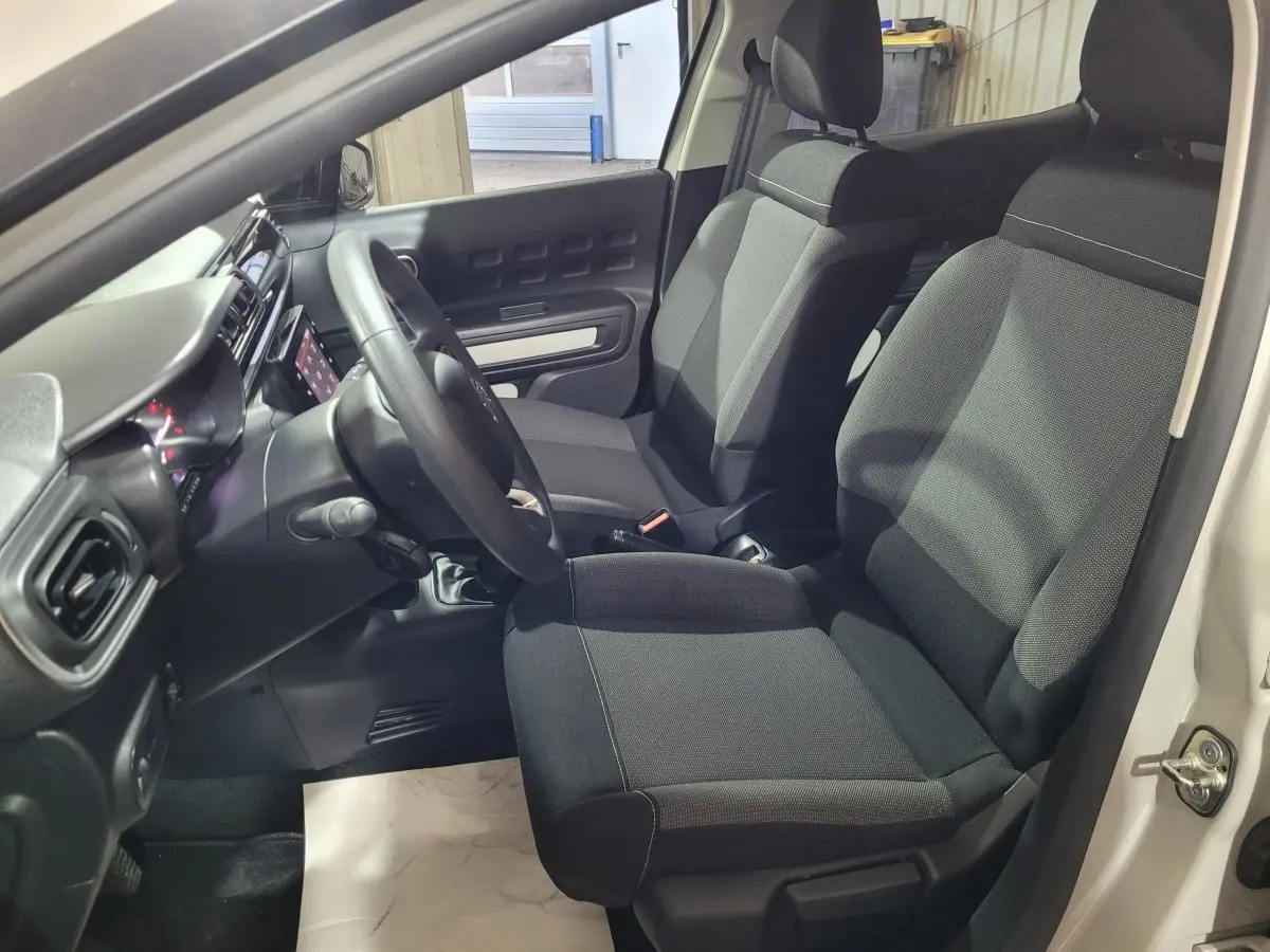 Vue intérieure côté conducteur de la Citroën C3 beige 2022, montrant les sièges noirs et le tableau de bord avec écran tactile.