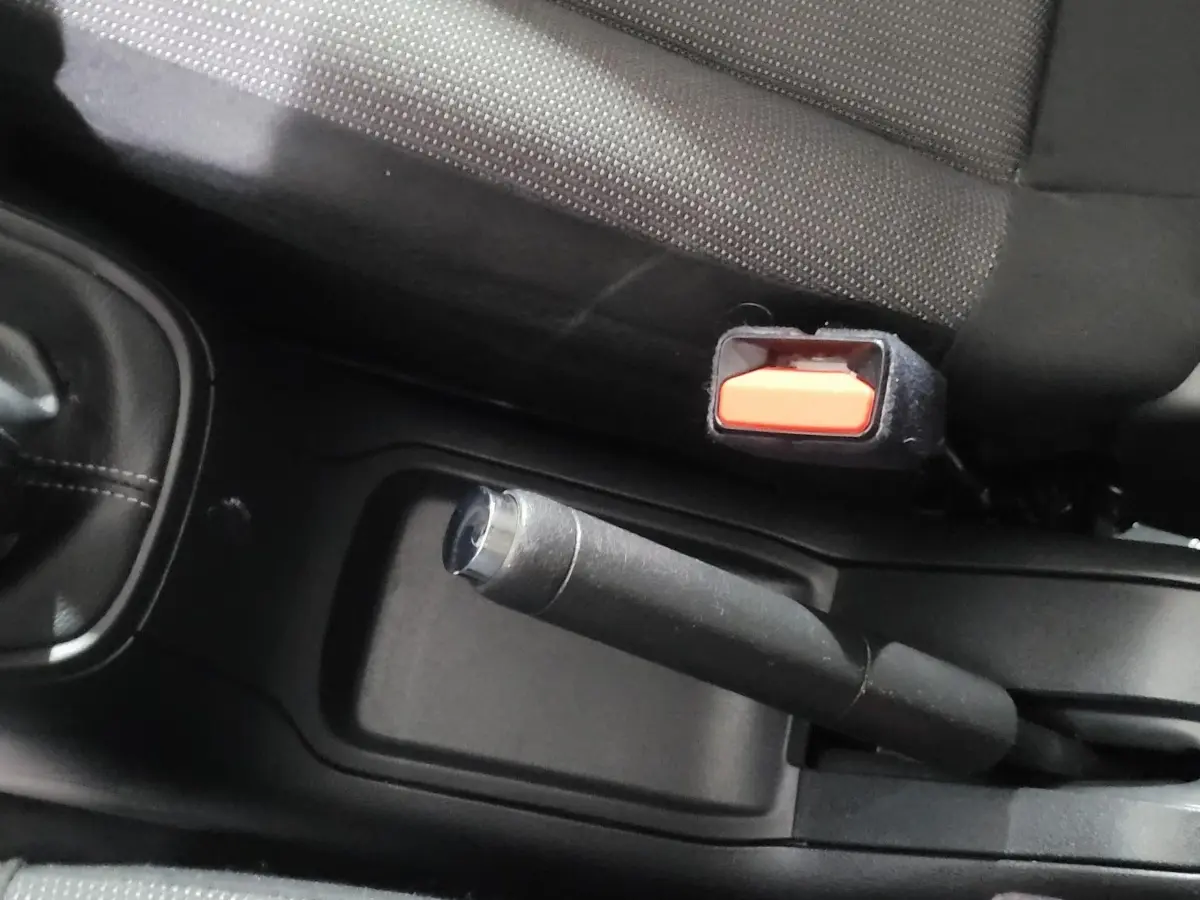 Gros plan sur le frein à main manuel et la ceinture de sécurité côté conducteur dans l’habitacle d’une Citroën C3 beige.