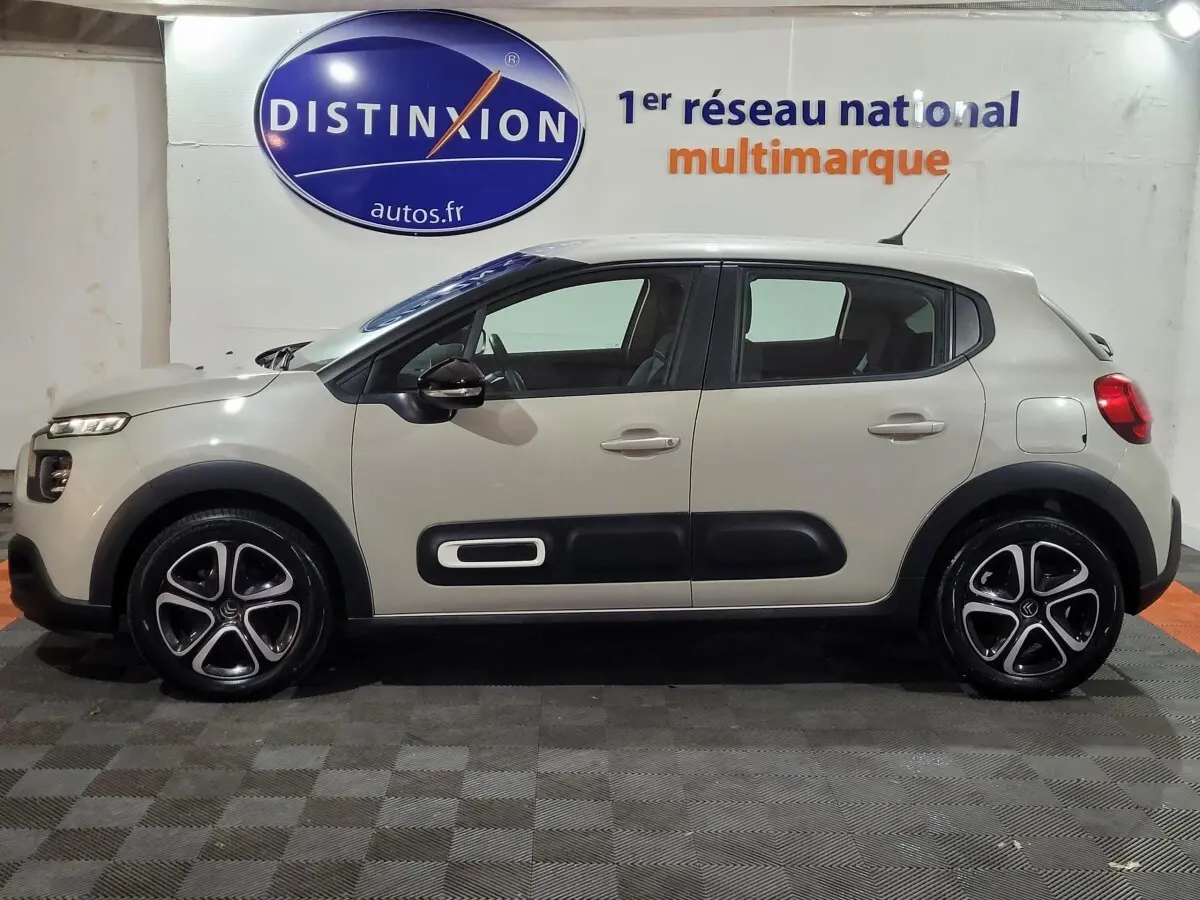 Vue de profil côté gauche d'une Citroën C3 beige 2022 avec protections latérales noires et jantes alliage distinctives.