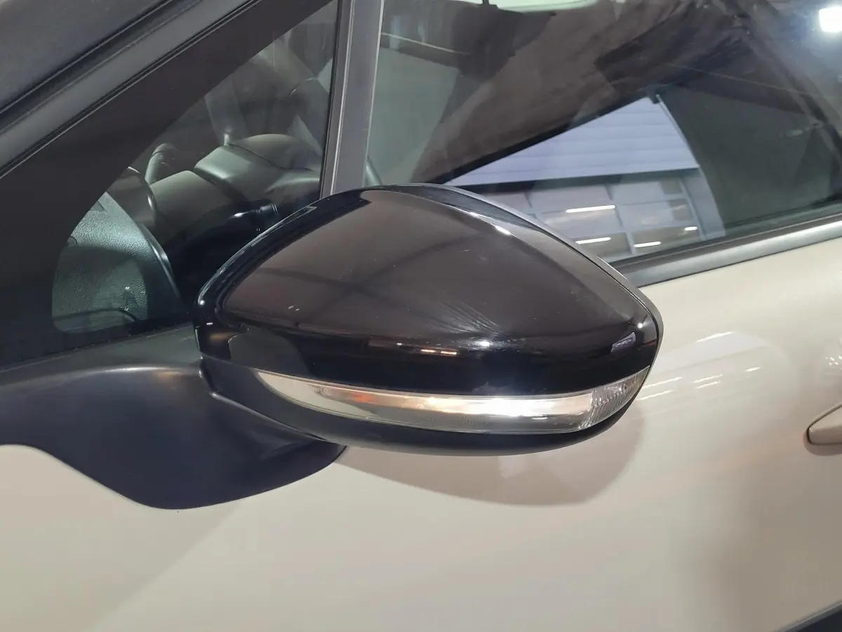 Rétroviseur extérieur noir en gros plan côté gauche d'une Citroën C3 beige 2022 avec clignotant intégré.