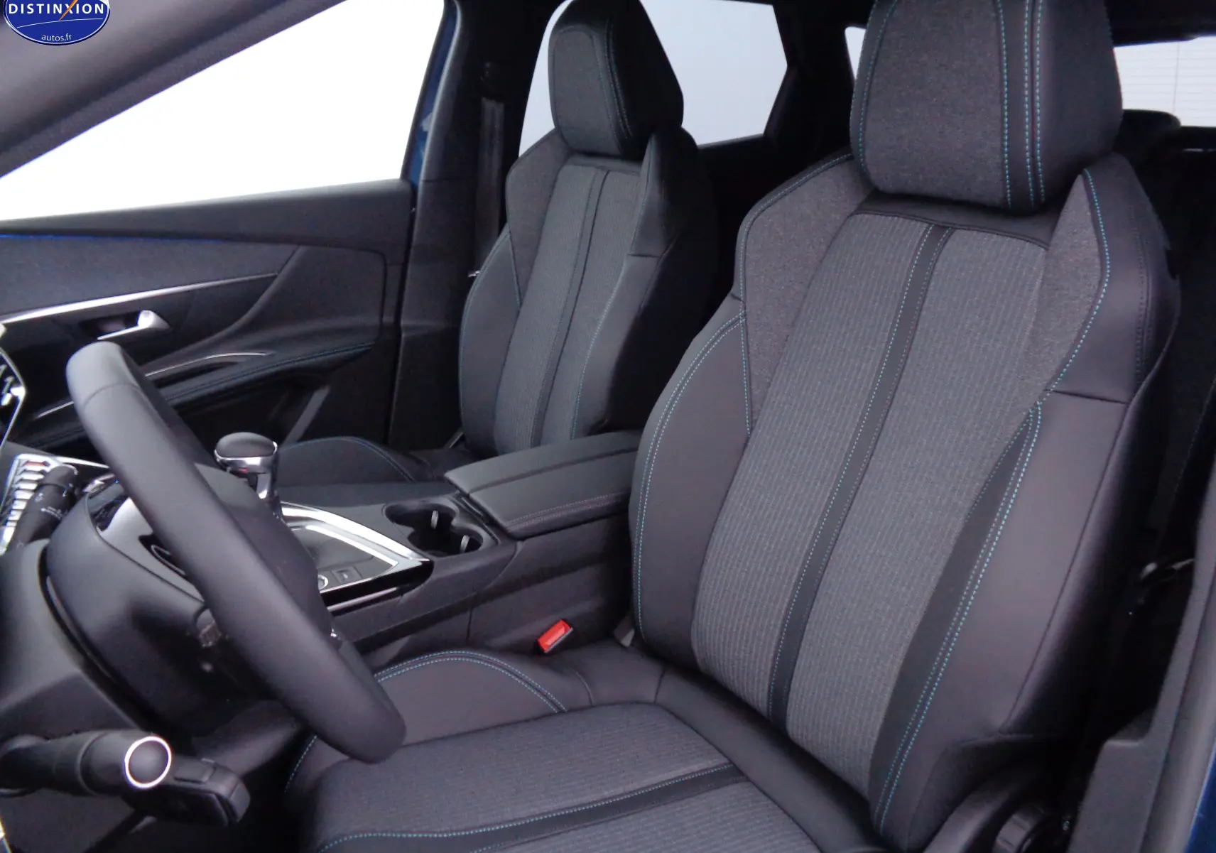 Vue intérieure côté conducteur du Peugeot 3008 2023 avec sièges en cuir noir et tissu gris à surpiqûres bleues.