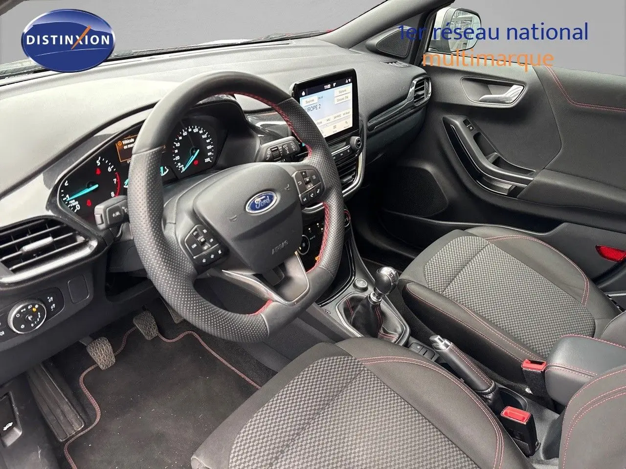 Intérieur du Ford Puma 2022 vu côté conducteur, tableau de bord moderne avec écran tactile et volant cuir perforé noir.