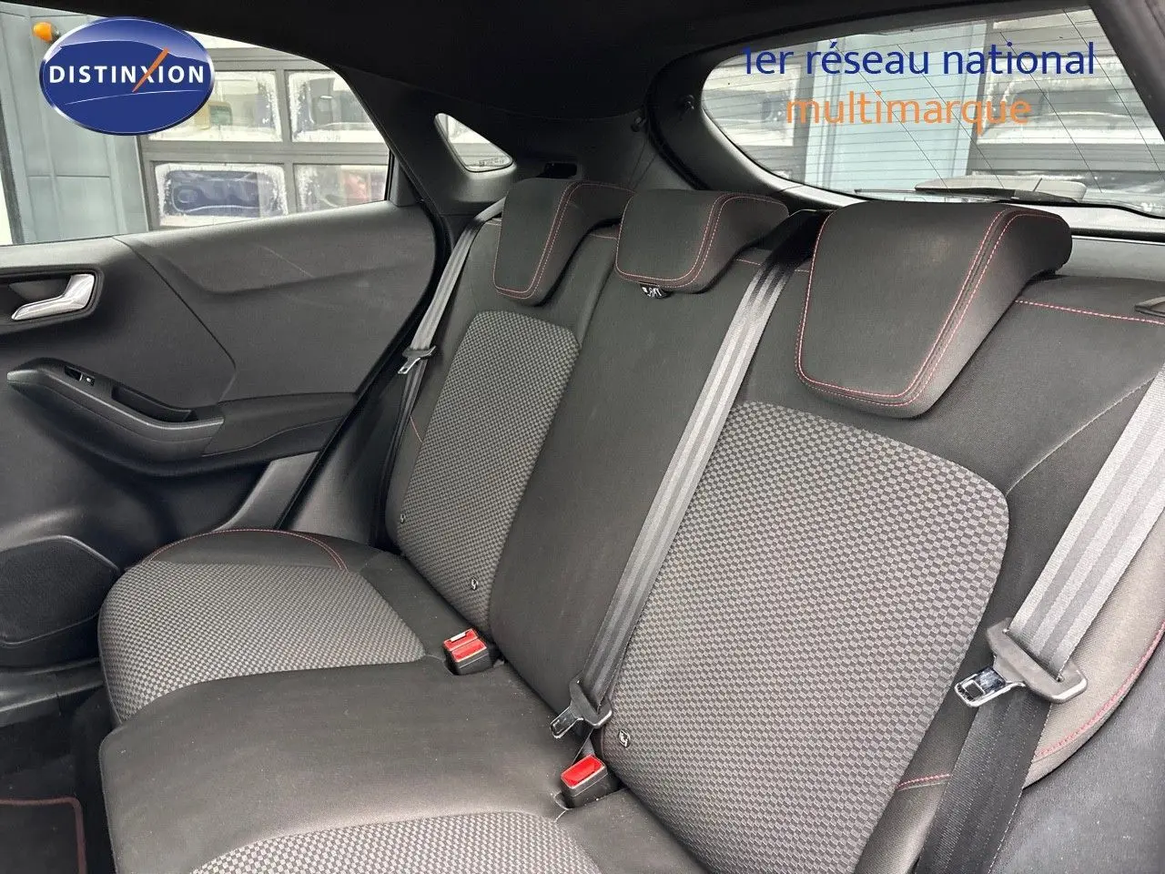Vue du siège arrière côté gauche d'une Ford Puma 2022, tissu noir avec surpiqûres rouges et ceintures grises.