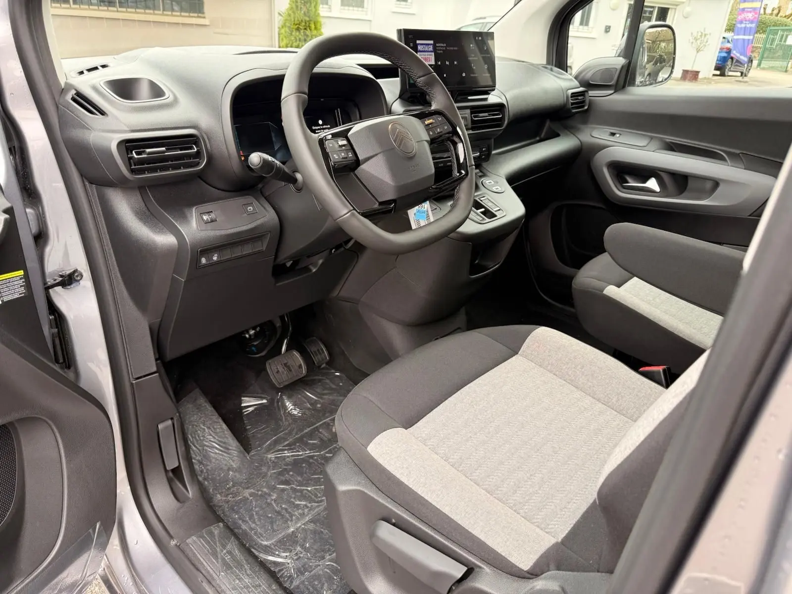 Vue intérieure côté conducteur du Citroën Berlingo gris Artense 2025, avec tableau de bord moderne et sièges bicolores.