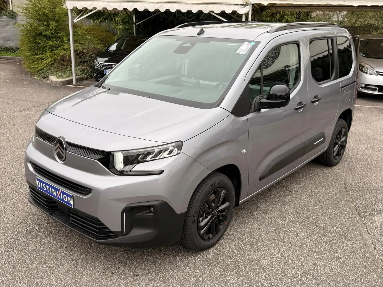 Vue 3/4 avant droit d'un Citroën Berlingo gris Artense avec jantes noires et détails noirs contrastants.
