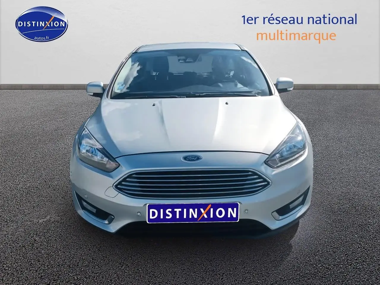 Vue avant d'une Ford Focus gris clair 2017 avec calandre chromée et phares halogènes allumés.