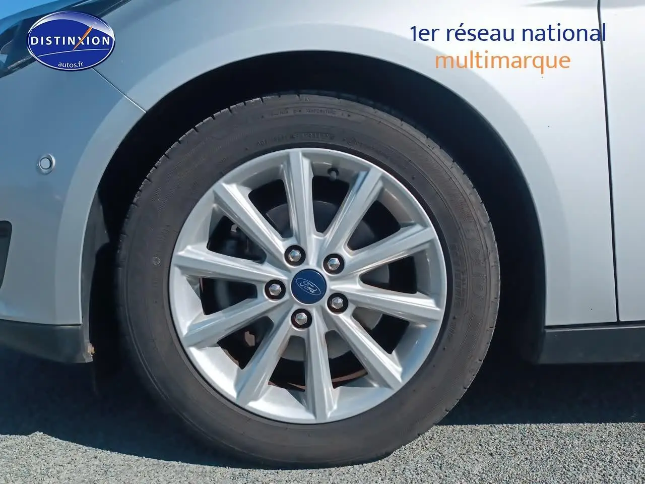 Gros plan sur la roue avant gauche en jante alu d'une Ford Focus gris clair 2017 finition Titanium.