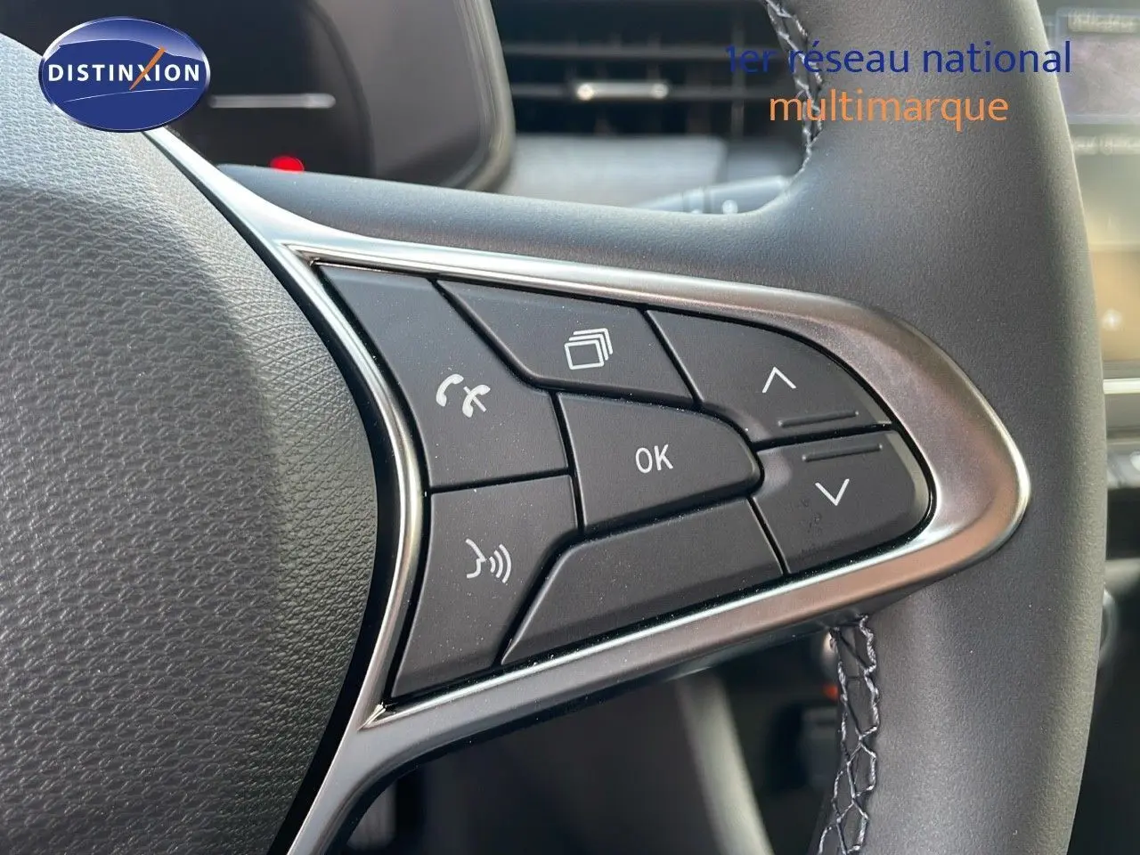 Gros plan sur les commandes au volant à droite d'une Renault Clio gris schiste métal 2025, avec boutons multifonctions.