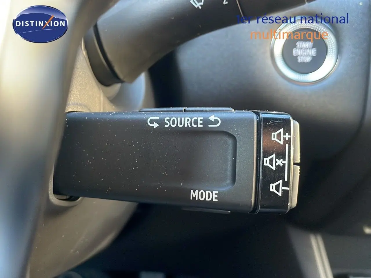 Gros plan sur la commande au volant du Renault Captur gris Cassiopée Métal, avec bouton source et mode visibles.