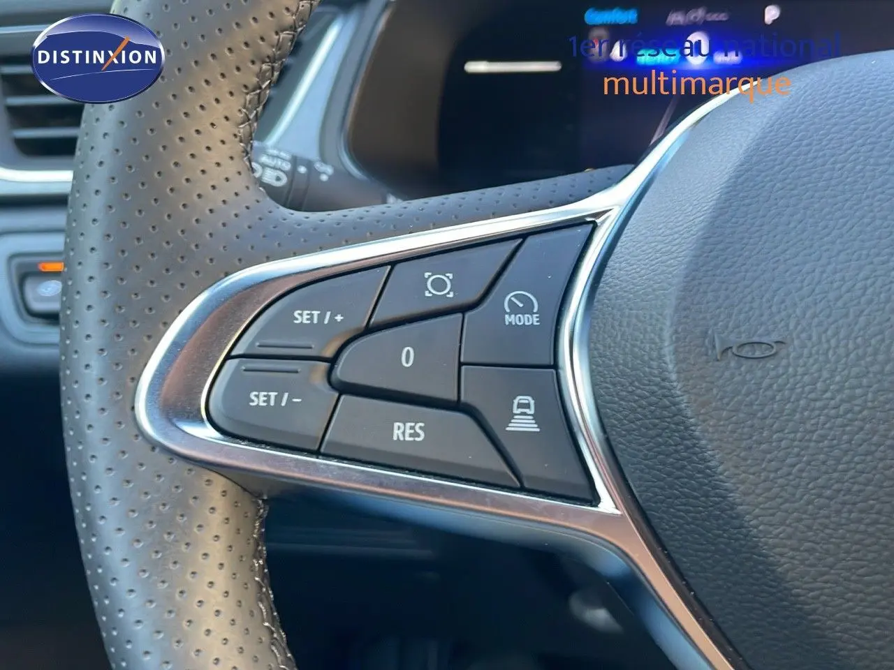 Gros plan sur les commandes au volant en cuir perforé du Renault Captur gris Cassiopée Métal 2025 hybride essence.