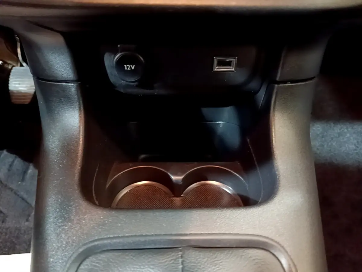 Gros plan sur la console centrale noire de la Citroën C3 avec prise 12V et port USB visible.