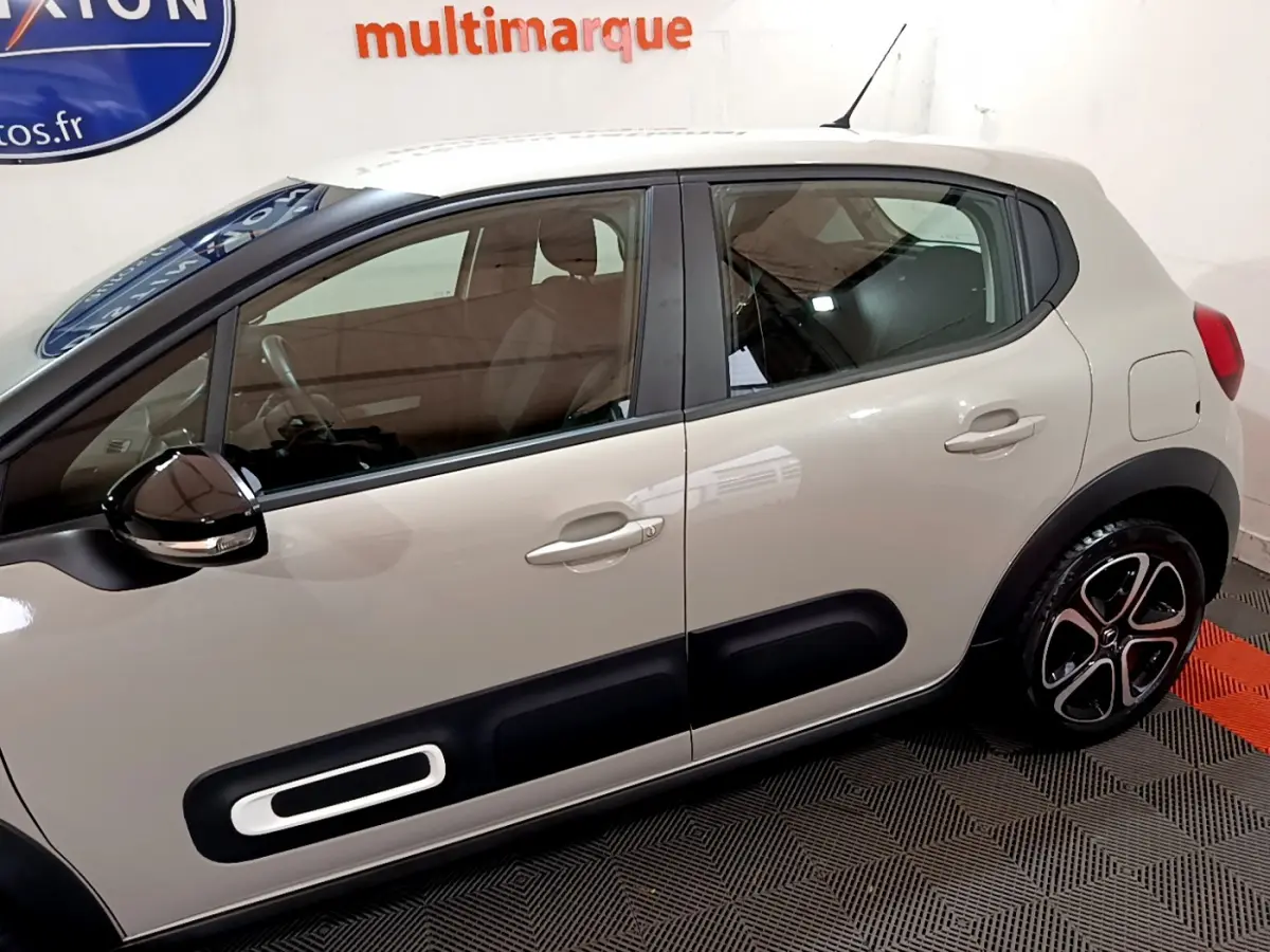 Vue de profil côté gauche d'une Citroën C3 beige 2022 avec protections latérales noires et jantes stylisées.