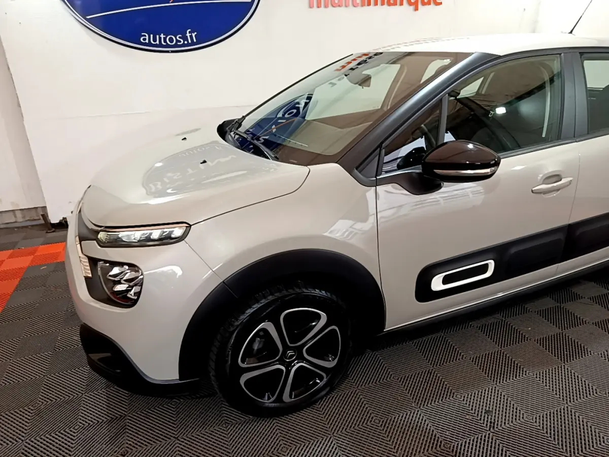 Vue 3/4 avant gauche d'une Citroën C3 beige avec protections latérales noires et jantes stylisées.