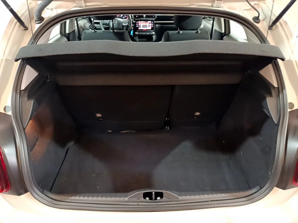 Coffre ouvert vu de l'arrière d'une Citroën C3 beige 2022, avec intérieur noir et tablette cache-bagages.