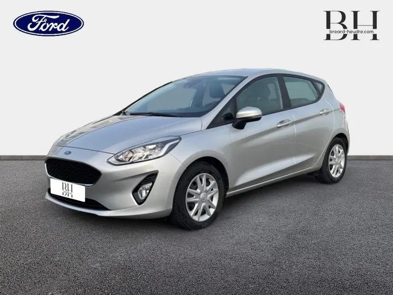 Vue 3/4 avant droite d'une Ford Fiesta 1.1 essence 2020 gris lunaire avec enjoliveurs et rétroviseurs argentés.