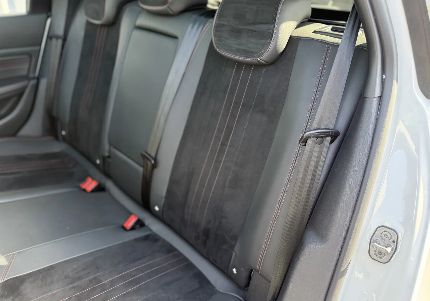 Vue intérieure côté droit des sièges arrière en cuir noir avec surpiqûres rouges du Peugeot 308 SW blanc nacré 2021.