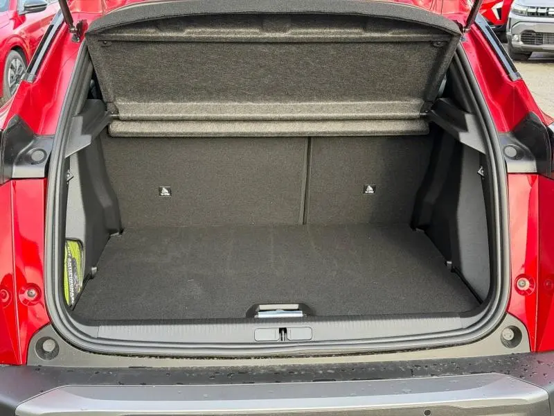 Coffre ouvert vu de l'arrière d'un Peugeot 2008 rouge, montrant l'espace de chargement vide et la tablette cache-bagages.