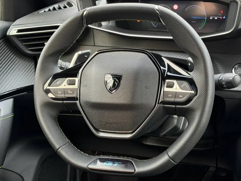 Vue rapprochée du volant cuir noir perforé avec logo Peugeot et badge GT du Peugeot 2008 Hybrid 145ch 2025.