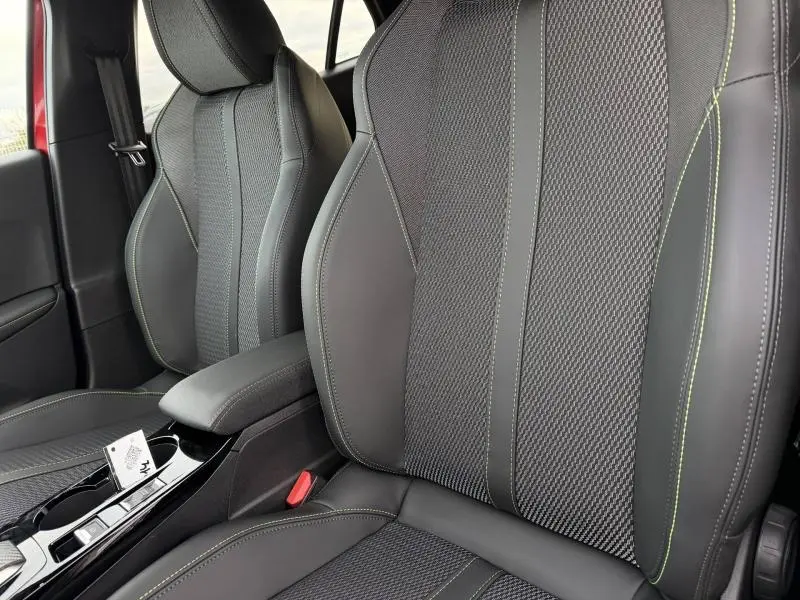 Gros plan sur les sièges avant en tissu et cuir noir avec surpiqûres vertes du Peugeot 2008 1.2 Hybrid 145ch GT 2025.