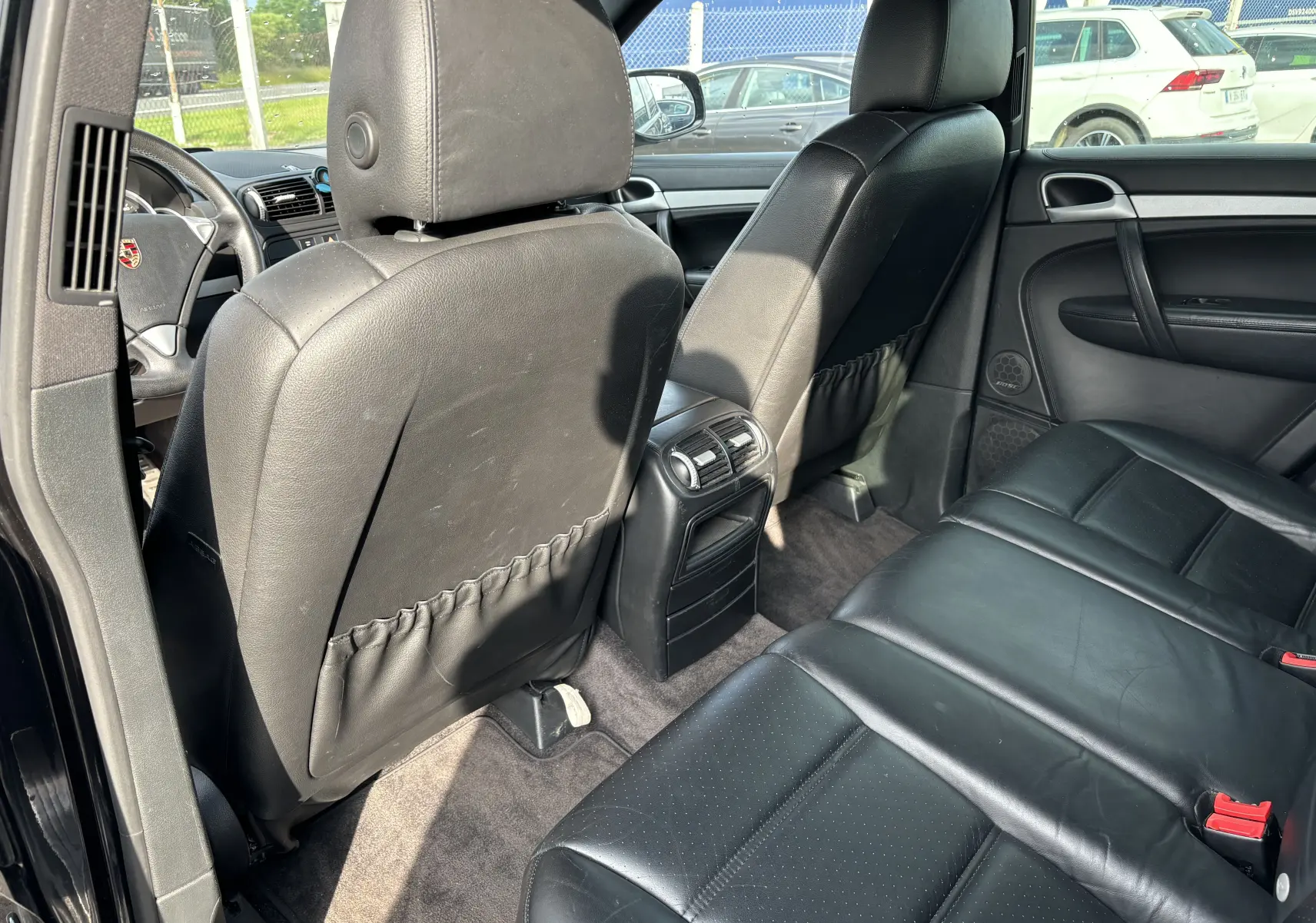 Vue intérieure arrière côté droit du Porsche Cayenne noir de 2007, montrant les sièges en cuir noir et la console centrale avec aérateurs.