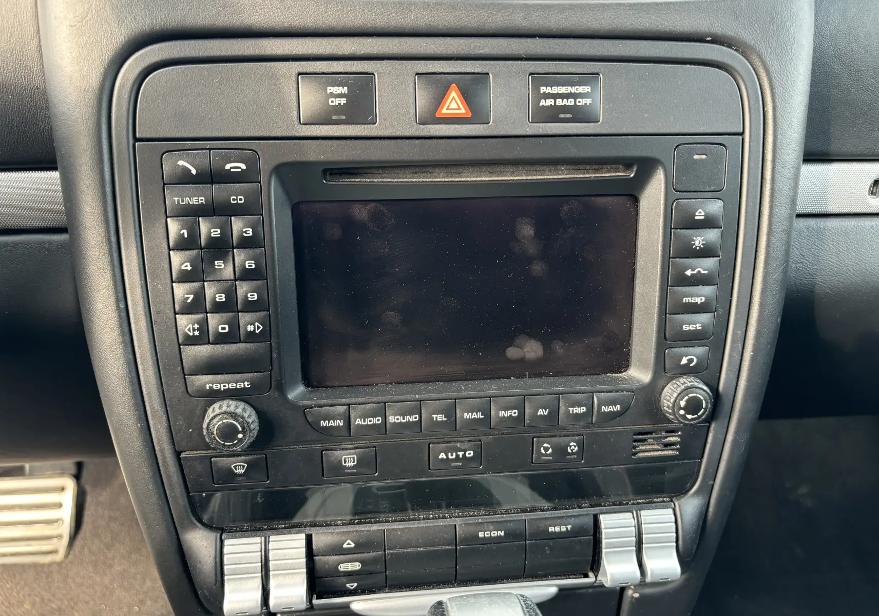 Vue rapprochée du tableau de bord noir d'une Porsche Cayenne 2007, mettant en valeur l'écran central et les commandes audio et climatisation.