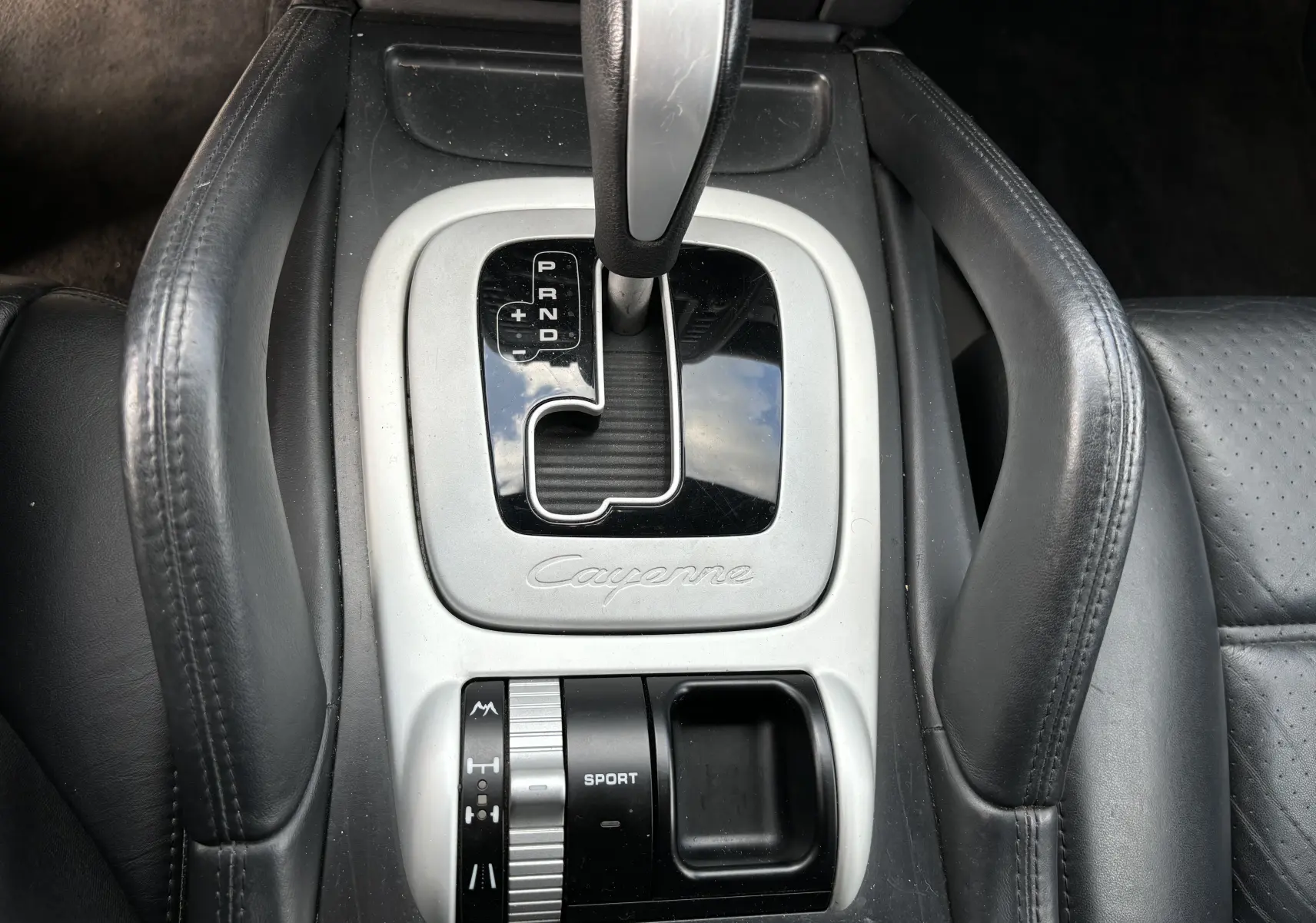 Vue rapprochée de la console centrale noire et argentée du Porsche Cayenne S 4,8L V8 avec levier de vitesses automatique et commandes sport.