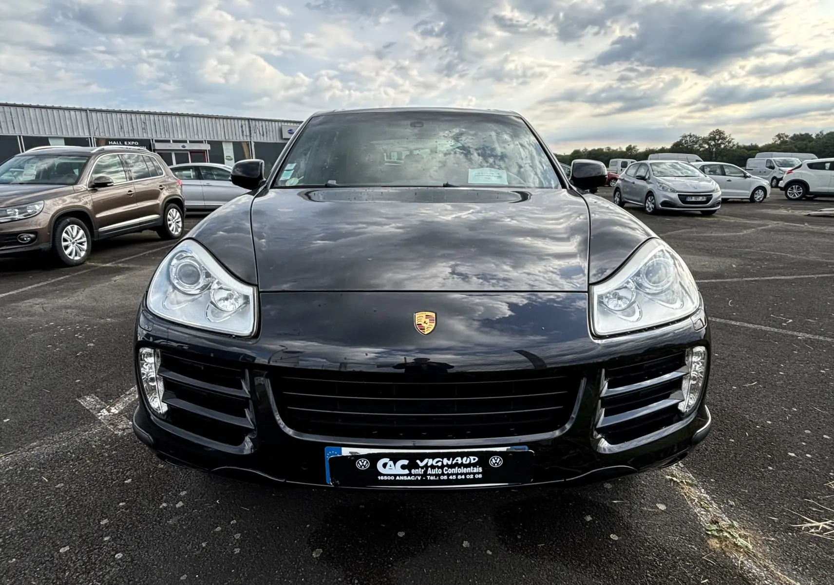 Vue frontale d'un Porsche Cayenne S 4,8L noir de 2007 avec phares distinctifs et calandre large sur parking extérieur.
