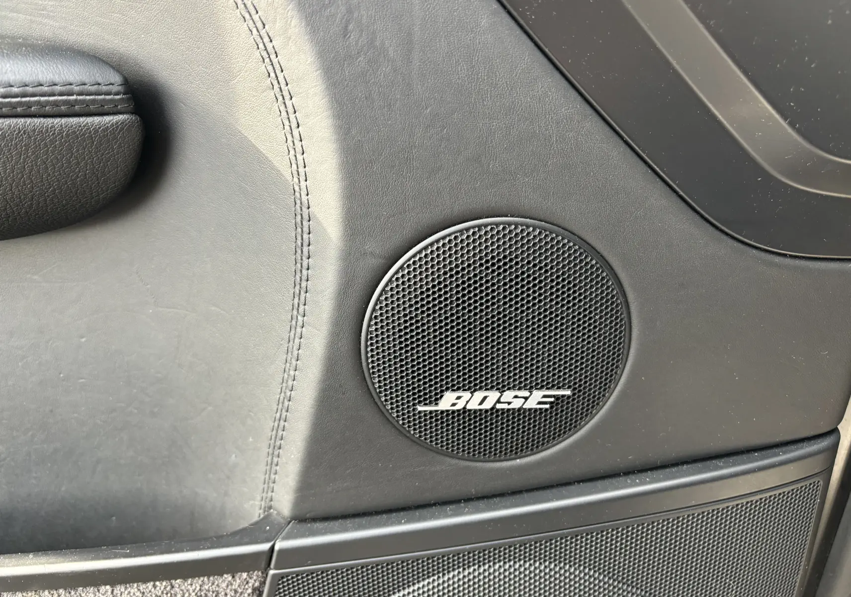 Gros plan sur l'enceinte Bose intégrée à la porte intérieure en cuir noir du Porsche Cayenne S 4,8L V8 de 2007.