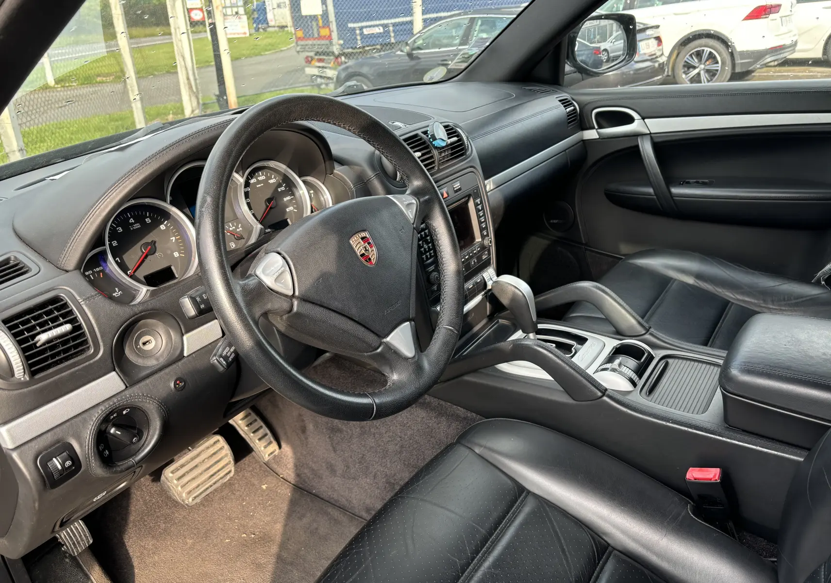 Intérieur noir du Porsche Cayenne S 4,8L V8 2007, vue côté conducteur sur le volant, tableau de bord et sièges cuir.