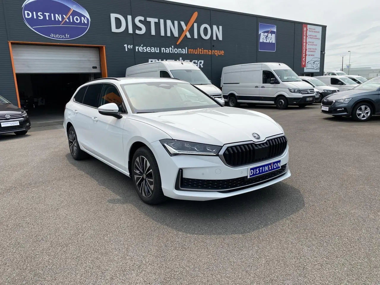 SKODA Superb Combi blanc pur vu de 3/4 avant droit, avec calandre noire et jantes alliage Alrakis 17 pouces.