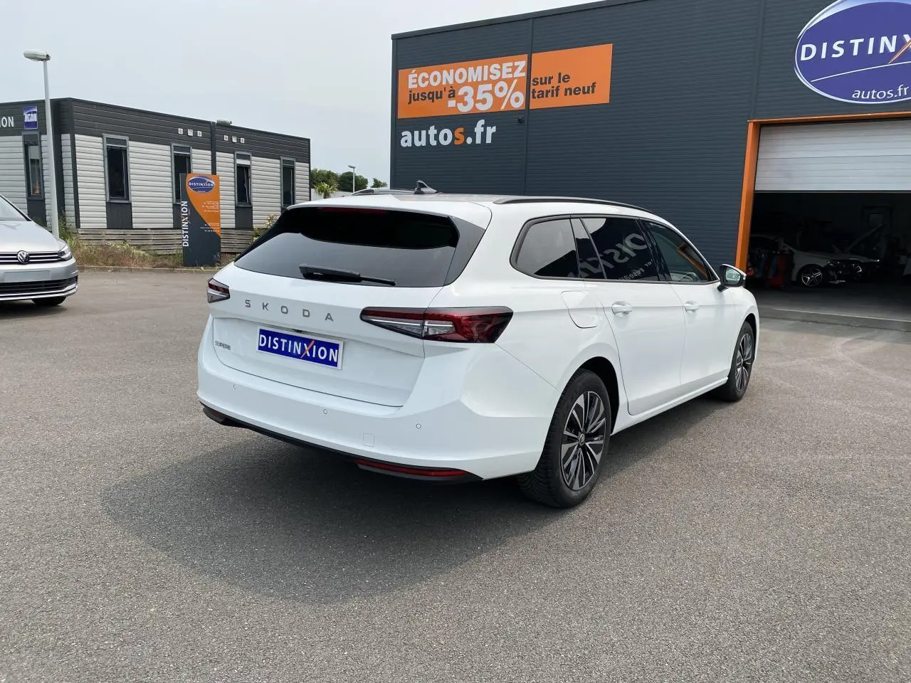 Vue 3/4 arrière droite d'une Skoda Superb Combi blanche pure avec vitres surteintées et jantes alliage noires polies.